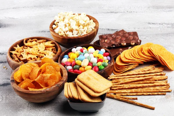 Salty snacks. Pretzels, chips, crackers in wooden bowls and cand — Stock Photo, Image