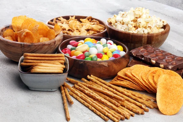 Salty snacks. Pretzels, chips, crackers in wooden bowls and cand — Stock Photo, Image