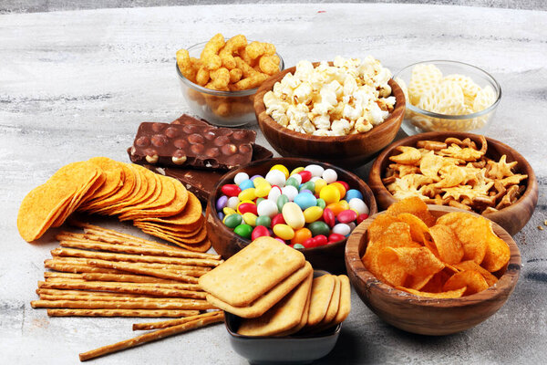 Соленые закуски. Крендельки, чипсы, крекеры в деревянных мисках и консервах
