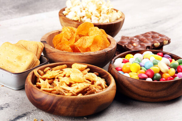 Salty snacks. Pretzels, chips, crackers in wooden bowls and cand