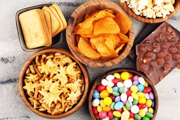 Соленые закуски. Крендельки, чипсы, крекеры в деревянных мисках и консервах — стоковое фото