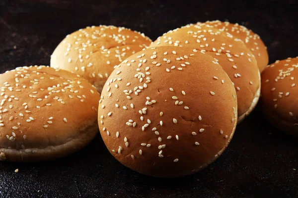 Koyu arkaplanda susamlı ev yapımı hamburger çörekleri.