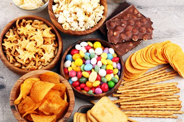 Salty snacks. Pretzels, chips, crackers in wooden bowls and cand — Stock Photo, Image