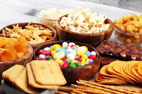 Salty snacks. Pretzels, chips, crackers in wooden bowls and cand — ストック写真