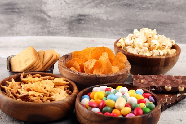 Salty snacks. Pretzels, chips, crackers in wooden bowls and cand — Stock Photo, Image