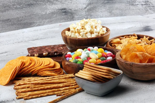 Salty snacks. Pretzels, chips, crackers in wooden bowls and cand — ストック写真