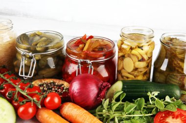 Sebzeleri cam kavanozlarda saklar. Salatalık turşusu, havuç, mayalanmış lahana ve soğan.