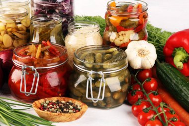 Sebzeleri cam kavanozlarda saklar. Salatalık turşusu, havuç, mayalanmış lahana ve soğan.