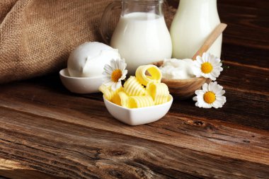 Süt ürünleri. Lezzetli sağlıklı süt ürünleri masada. Bir kasede mozzarella, süzme peynir kasesi, tereyağı girdabı ve cam şişe. 