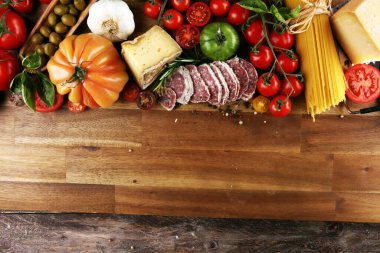 Masadaki İtalyan yemekleri için domates, makarna, sebze, bitki ve baharat.