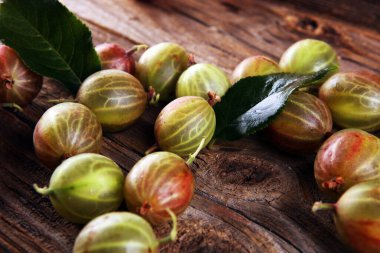 Ahşap arka planda Bektaşi üzümü meyveleri. Kırmızı ve yeşil olgun bektaşi üzümleri masada.