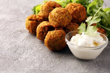 Arka planda sarımsaklı yoğurt soslu nohut köftesi.