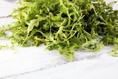 Arka planda roka salatası. Masada yeni toplanmış roka salatası.