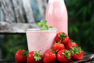 Bir bardak taze çilekli süt, smoothie veya milkshake ve taze çilek. Sulu meyveli sağlıklı yiyecek ve içecek konsepti 