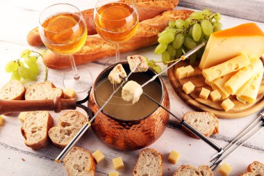 Bir kış akşamı gurme İsviçre fondü yemeği tahtanın üzerinde çeşitli peynirlerle birlikte çatallı ve peynirli fondü. 