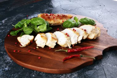 Kısmen dilimlenmiş ızgara tavuk göğsü. Köy arka planında kesim tahtası.