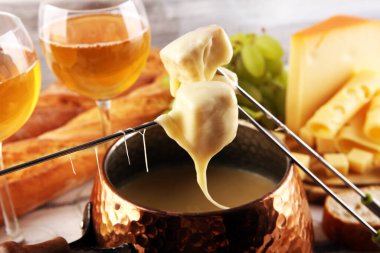 Bir kış akşamı gurme İsviçre fondü yemeği tahtanın üzerinde çeşitli peynirlerle birlikte çatallı ve peynirli fondü. 