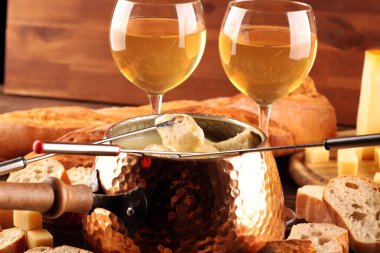 Bir kış akşamı gurme İsviçre fondü yemeği tahtanın üzerinde çeşitli peynirlerle birlikte çatallı ve peynirli fondü. 