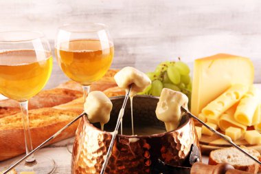 Bir kış akşamı gurme İsviçre fondü yemeği tahtanın üzerinde çeşitli peynirlerle birlikte çatallı ve peynirli fondü. 