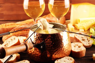 Bir kış akşamı gurme İsviçre fondü yemeği tahtanın üzerinde çeşitli peynirlerle birlikte çatallı ve peynirli fondü. 