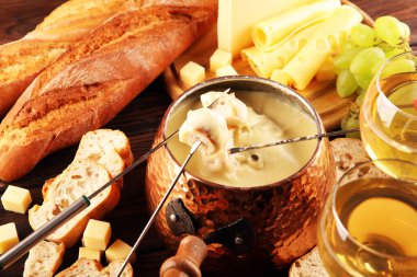 Bir kış akşamı gurme İsviçre fondü yemeği tahtanın üzerinde çeşitli peynirlerle birlikte çatallı ve peynirli fondü. 