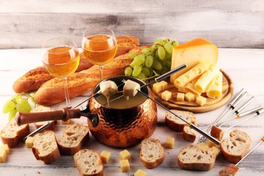 Bir kış akşamı gurme İsviçre fondü yemeği tahtanın üzerinde çeşitli peynirlerle birlikte çatallı ve peynirli fondü. 