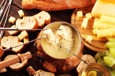 Bir kış akşamı gurme İsviçre fondü yemeği tahtanın üzerinde çeşitli peynirlerle birlikte çatallı ve peynirli fondü. 