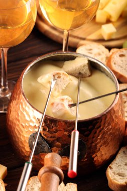 Bir kış akşamı gurme İsviçre fondü yemeği tahtanın üzerinde çeşitli peynirlerle birlikte çatallı ve peynirli fondü. 