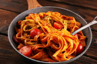 Domates soslu tagliatelle makarnası. Köy masasında parmesan fesleğeni.