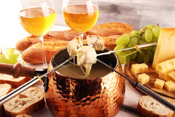 Bir kış akşamı gurme İsviçre fondü yemeği tahtanın üzerinde çeşitli peynirlerle birlikte çatallı ve peynirli fondü. 