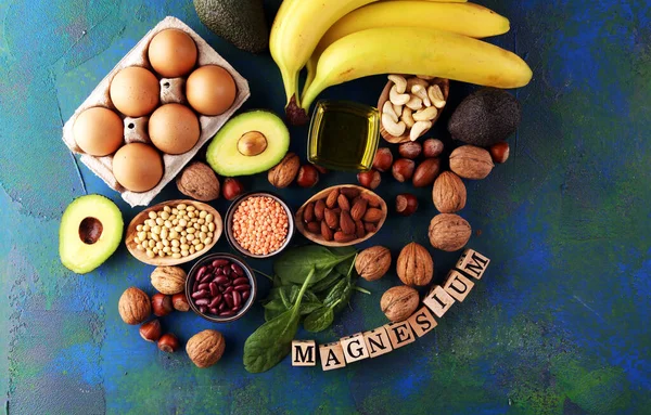 Products containing magnesium: bananas, almonds, avocado, nuts and spinach and eggs on table