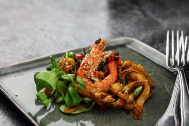 Gurme bir restoranda öğle yemeği yemeği. Yemek, balık, nefis bir gurme tabağı. Koyu tabakta deniz ürünleri karidesi