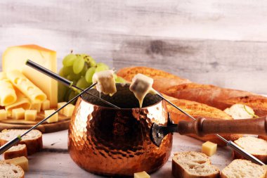 Bir kış akşamı gurme İsviçre fondü yemeği tahtanın üzerinde çeşitli peynirlerle birlikte çatallı ve peynirli fondü. 