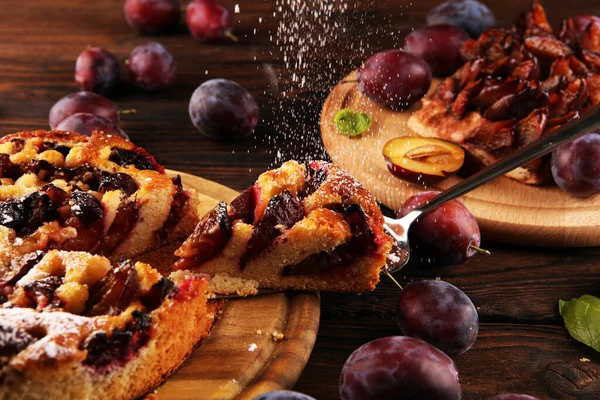 Rustic plum cake on wooden background with plums around. Plum pie concept