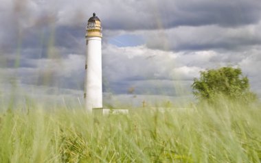Deniz feneri, yeşil çimen ve mavi gökyüzü arkaplanı