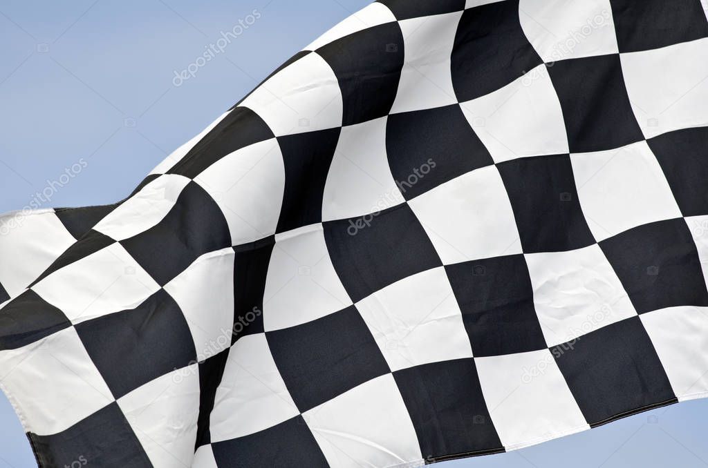 checkered flag on wind in front of blue sky