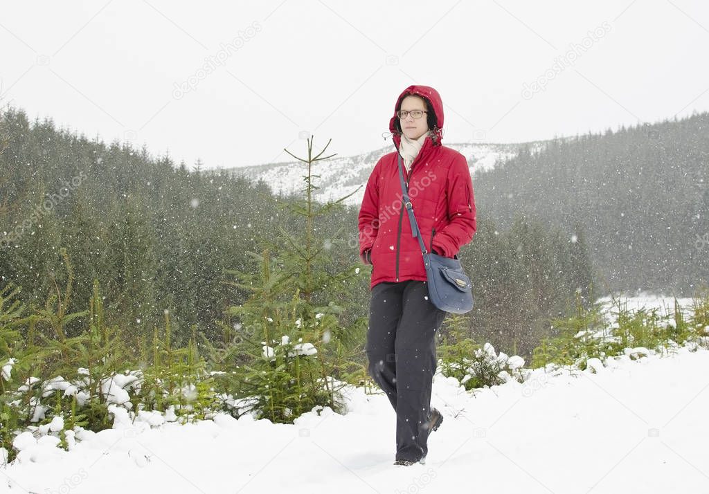 young woman in red jacket walking during have snow weather