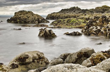 deniz suyu bulutlu gökyüzü altında kayalarda