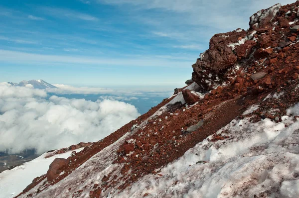 Slope of Avachinsky Volcano. Red volcanic rocks. Zhupanovsky Volcano in the distance. Nalychevo Nature Park, Kamchatka Krai, Russia