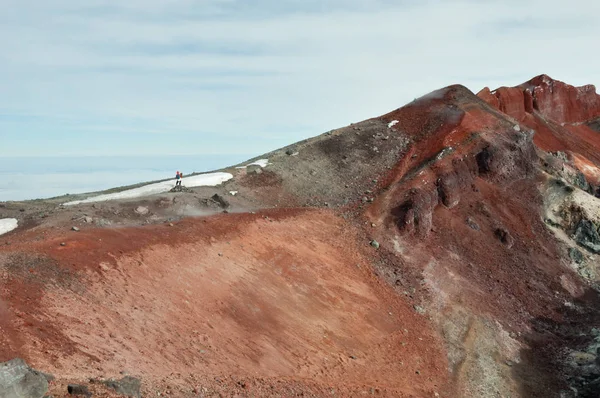 At the top of Avachinsky volcano. Igneous rock formed surreal martian landscape at the top of Avachinskaya Sopka. Small human figure is standing at the edge of the crater. Nalychevo Nature Park, Kamchatka Krai, Russia