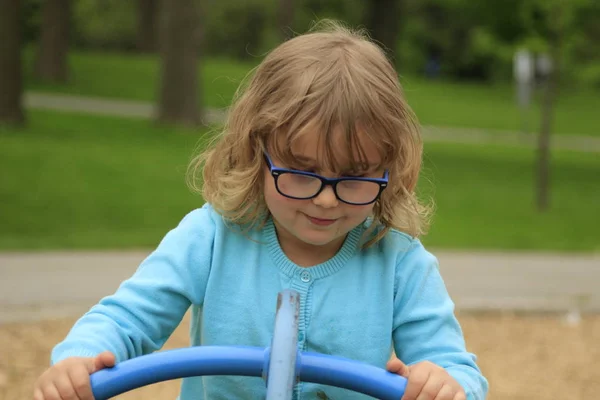 Dziewczynka z okulary i niebieską koszulę, grając na plac zabaw w szkole w wieku od 3 do 5 — Zdjęcie stockowe