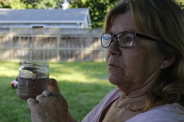 Äldre kvinnor i åldrarna 60 till 65 dricks vatten utomhus — Stockfoto