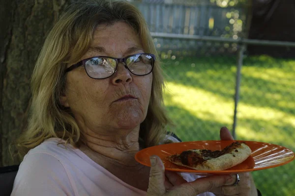 60岁至65岁的老年妇女在外面的露台上吃比萨饼 — 图库照片