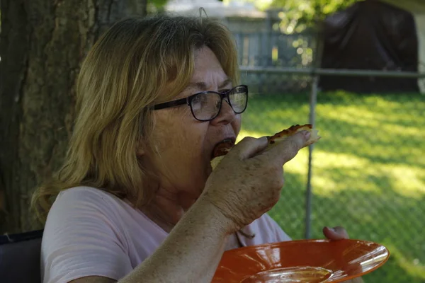 Older senior women aged 60 to 65 eating pizza on patio outside — Stock Photo, Image
