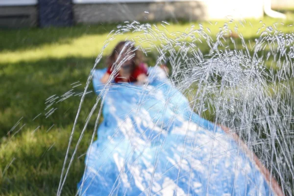 Lachende meisje glijdend van een buiten slip en slide. selectieve aandacht op water voor kind — Stockfoto