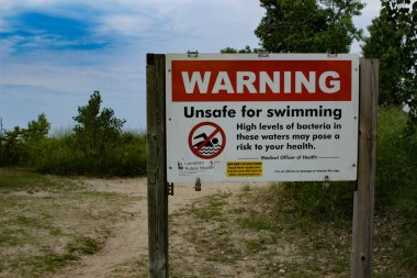 Güney Ontario 'daki Ipperwash plajında uyarı tabelası. Eğer yüzerseniz bakterilerin size zarar verebilmesini sağlayan bir uyarı vardır. Yüzme işareti yok.