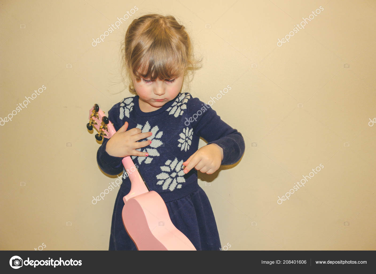 Young Girl Aged 3 To 5 Years Old Holding A Ukelele And Learning