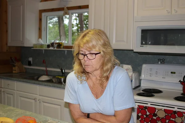 Close up Thoughtful Middle Aged Blond Woman, Sitting at the Living Room and Looking Up with Hands on the Chin. — Stock Photo, Image