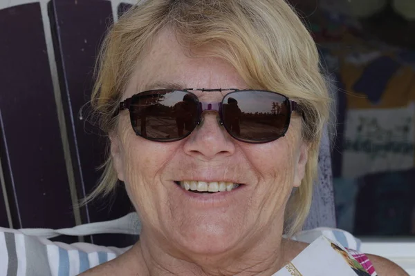 Close up portrait of beautiful older woman smiling and standing by wall — Stock Photo, Image