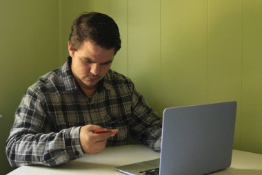 Ciddi adam online ödeme kredi kartı ve dizüstü bilgisayar, genç adam bilgisayar ekranına, güvenli ödeme yapmadan müşteri tüketici bakarak web bankacılık hizmetini kullanarak Internet satın alma ile alışveriş satın alma